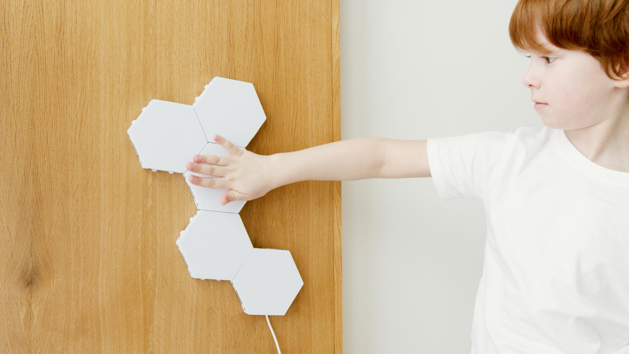 A child interacts with geometric wall tiles, creating a playful and educational moment.